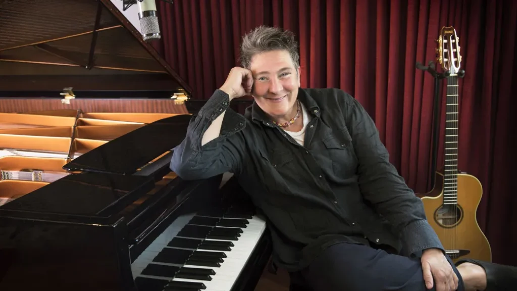 Kd Lang, seated, leaning on a piano - Illustration of the Fortune Kd Lang article.