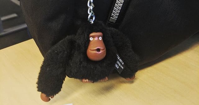 Porte-clés gorille Kipling posé à côté d'un flyer, incarnant l'esprit ludique et entrepreneurial de Tony Gram.