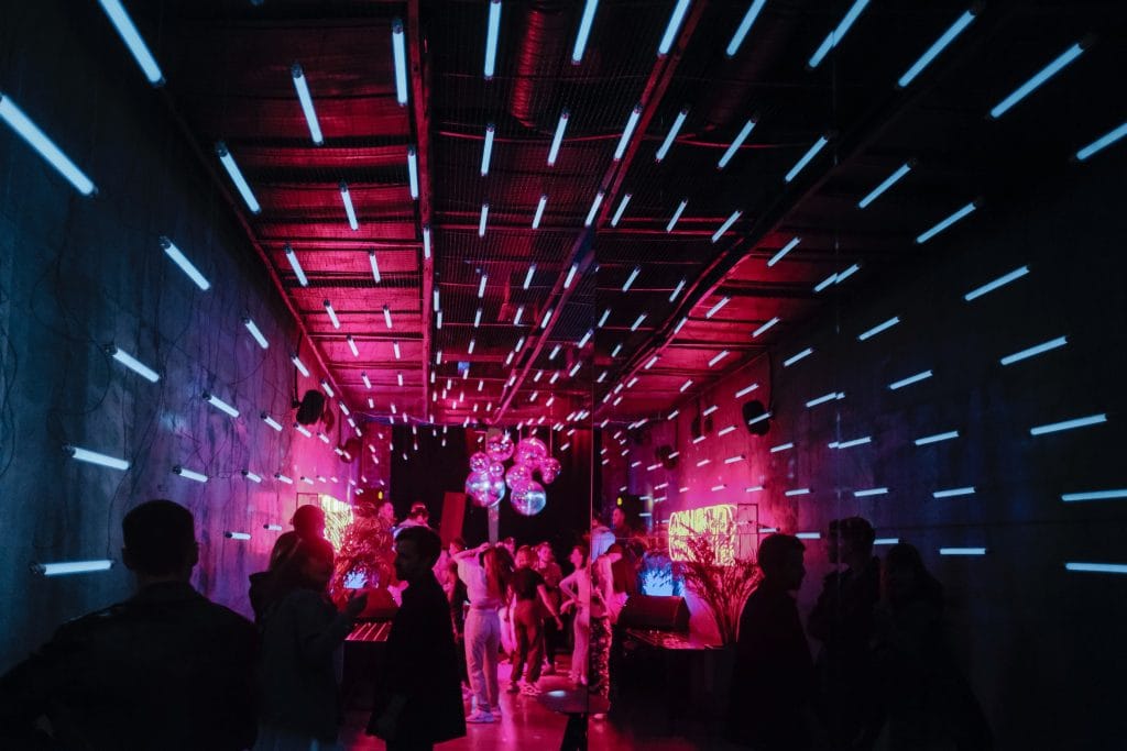 Firmenfeier unter vibrierendem Neonlicht, innovativer Stil, der die Vision von Glenn Janssens für Trafiroad widerspiegelt.