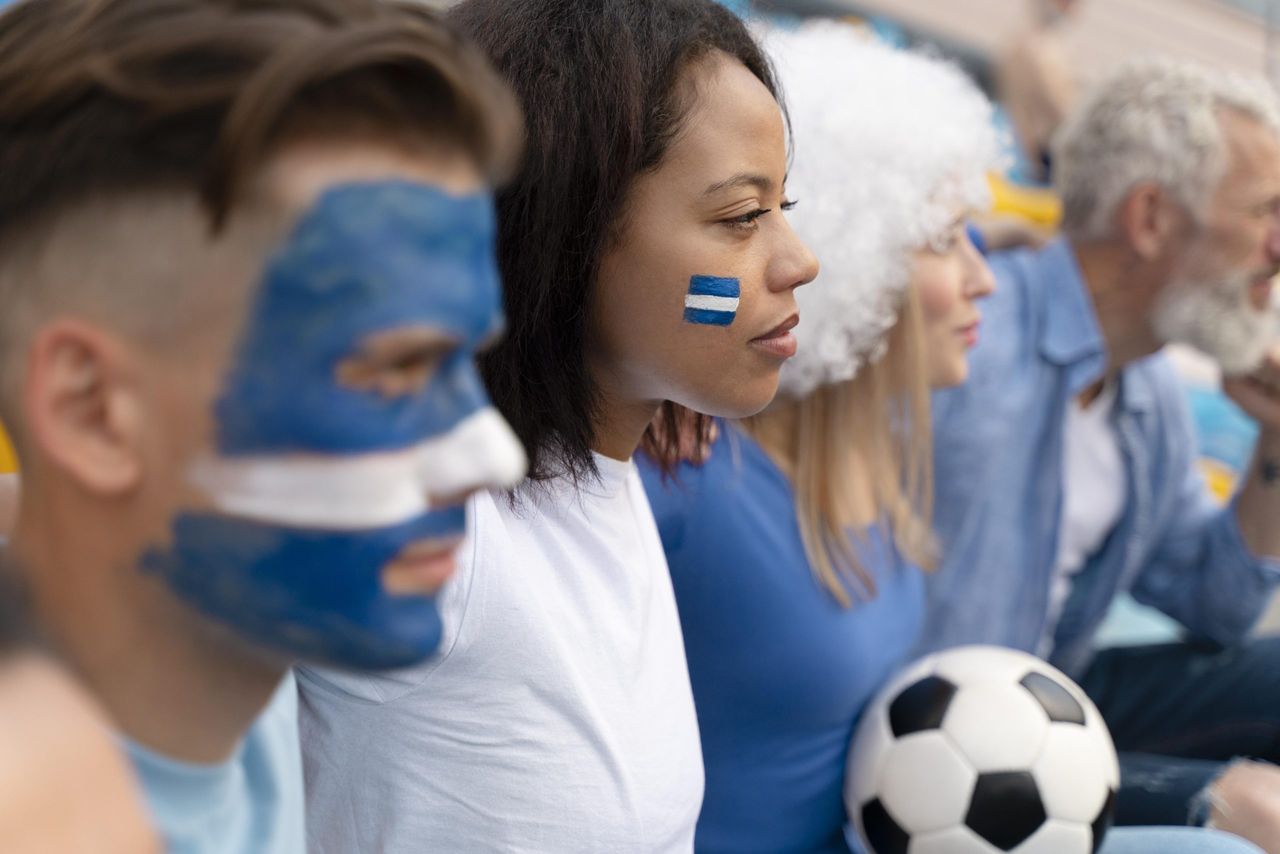 Group of supporters wearing blue and white face paint, the colors of the AA Gent soccer team.