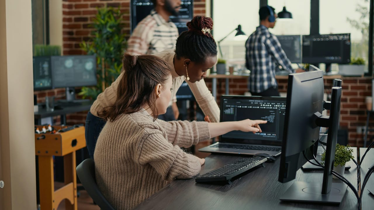 Odoo employees examining code on a monitor, an exchange that demonstrates the team spirit and knowledge sharing encouraged by Fabien Pinckaers.