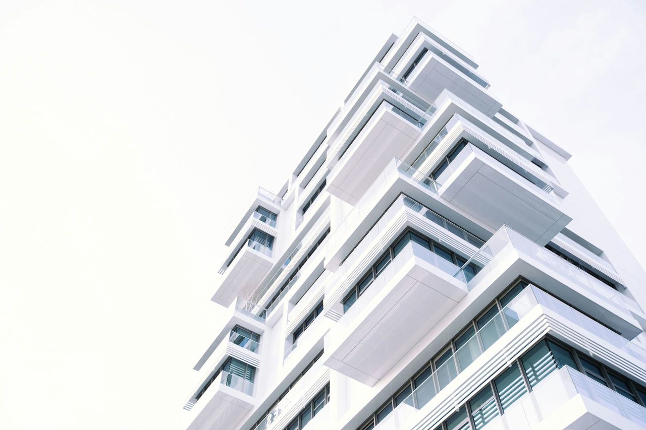 Contemporary white residential building under a clear sky, reflecting the real estate expertise of Yves Puttemans and Dominique Van Etterijk at Dyls.