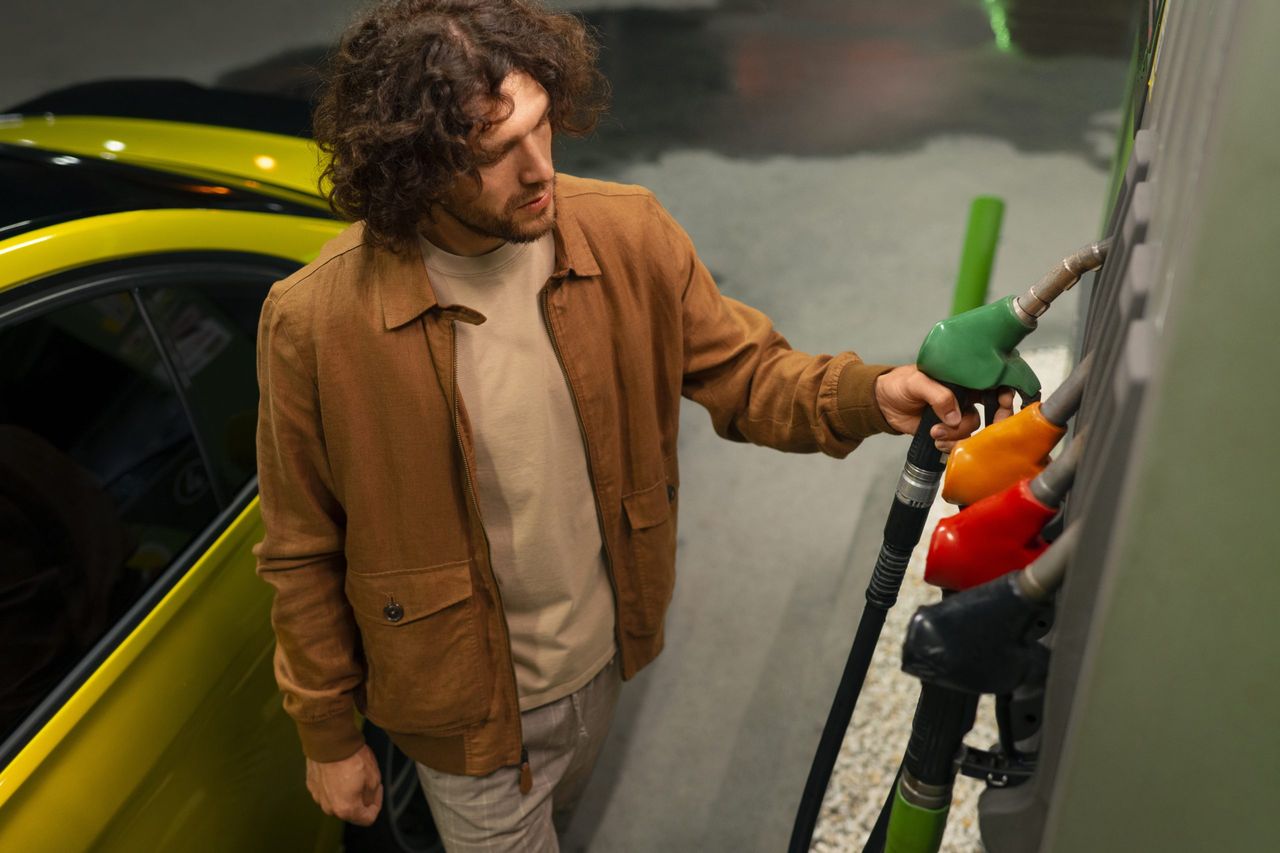 Man refueling his car at a gas station, echoing the Uhoda family's distribution network.