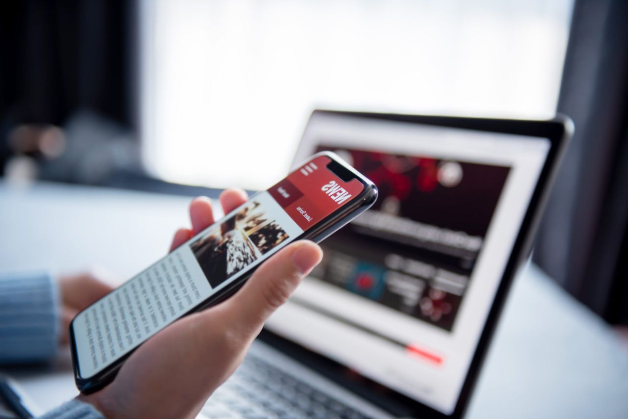 Smartphone et ordinateur affichant les actualités en ligne, représentant la stratégie numérique de la famille Van Thillo.