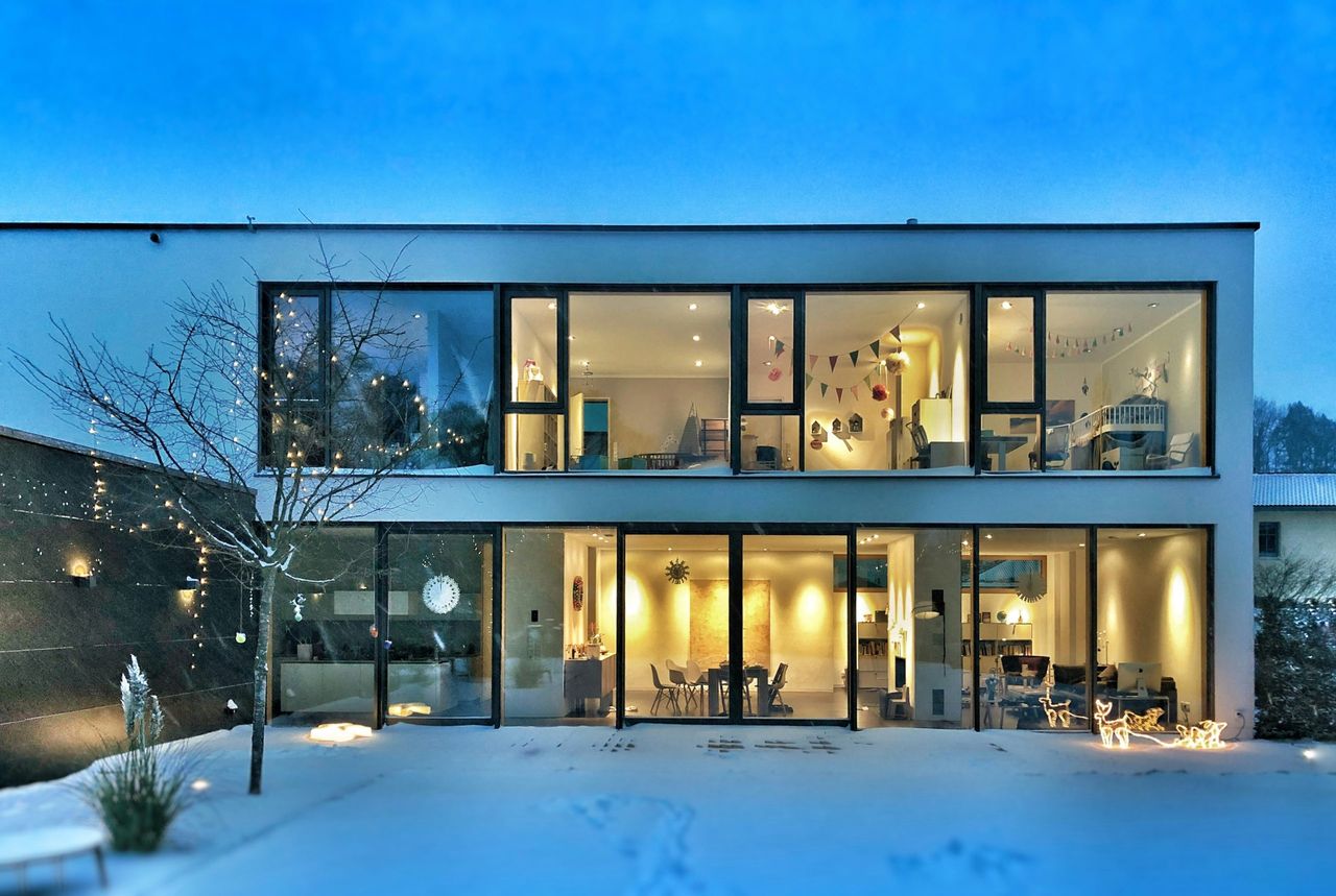 Modernes Haus im Winter in der Abenddämmerung, das die Stärke und Einheit der Familie Weerts symbolisiert.